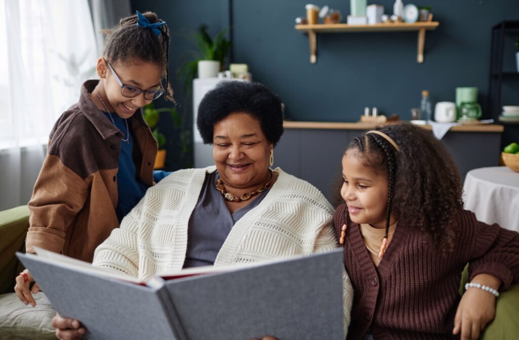 A grandparent with their grandchildren spending time together during the transition into memory care; looking through a photo album