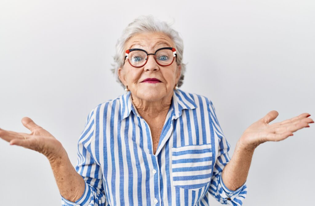 An older adult shrugs and raises their hands, feeling unsure.