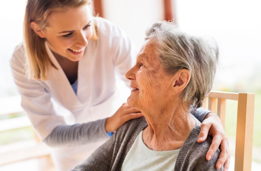 A caregiver checks in on a smiling resident on a warm afternoon in memory care