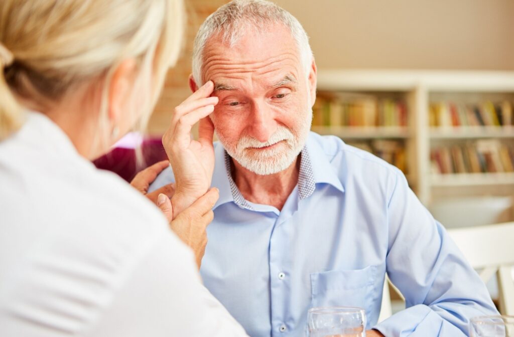 An older senior touches their temple as they struggle to remember